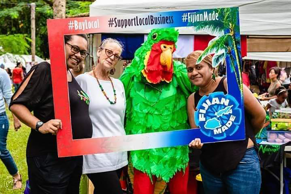 People posing in a large cut out picture frame, one of the people is dressed in a bird suit.